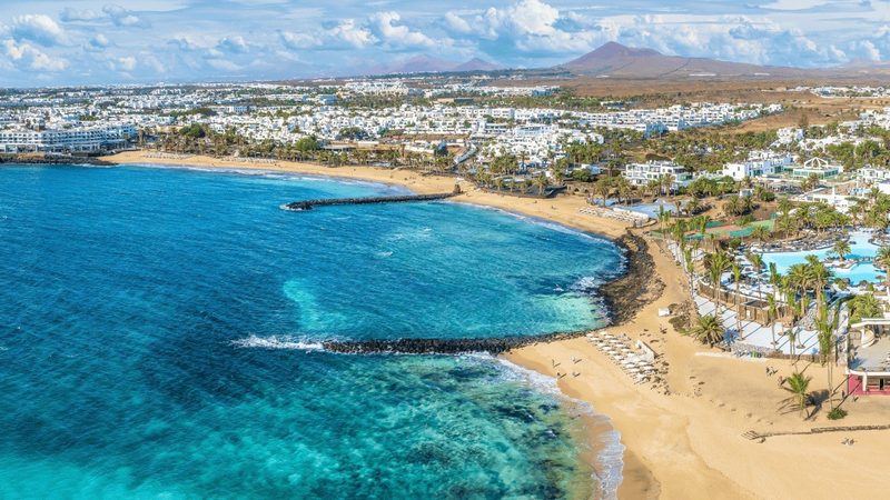 Costa Teguise Lanzarote aerial view — beach resort town with turquoise water and white buildings along the coastline