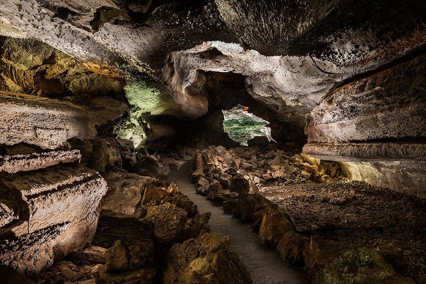 Cueva de los Verdes Lanzarote — volcanic lava tunnel interior with textured basalt walls, warm ambient lighting and natural rock formations