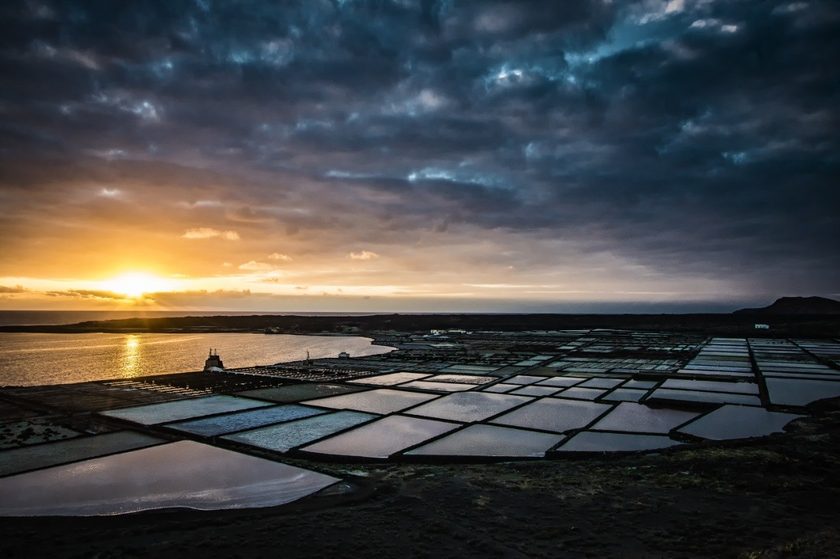 Sunset at El Golfo Lanzarote — green lagoon and volcanic black sand beach with dramatic sky and ocean reflecting orange and purple light