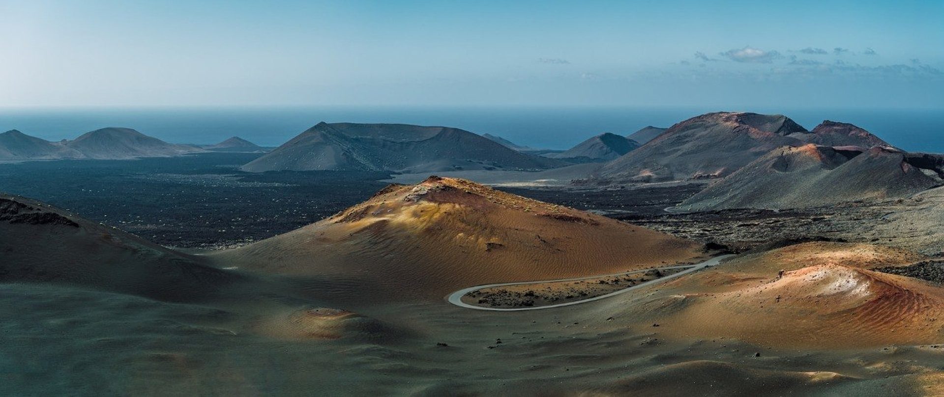 Timanfaya volcanic landscape Lanzarote — rust-red mountains and lava fields under dramatic cloudy sky at the Fire Mountains National Park