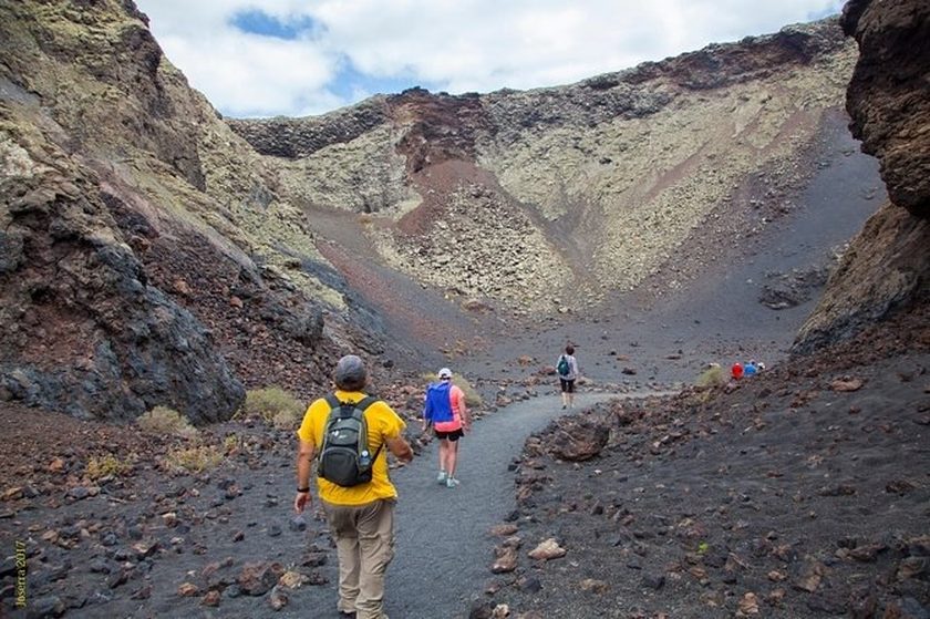 Volcano hiking tour Timanfaya Lanzarote — guided trek through volcanic craters and lava fields with hikers on the caldera rim